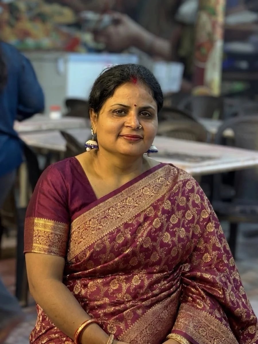 Elegant woman in a deep maroon and gold saree, seated portrait